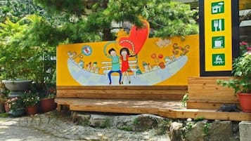 A colorful mural with a heart-shaped design, a bench, and a sign with icons indicating amenities.