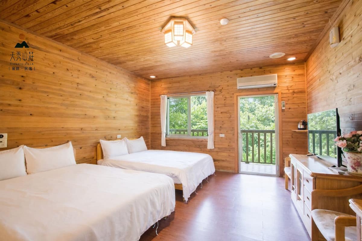 A wooden cabin with two beds, a balcony, and a TV.