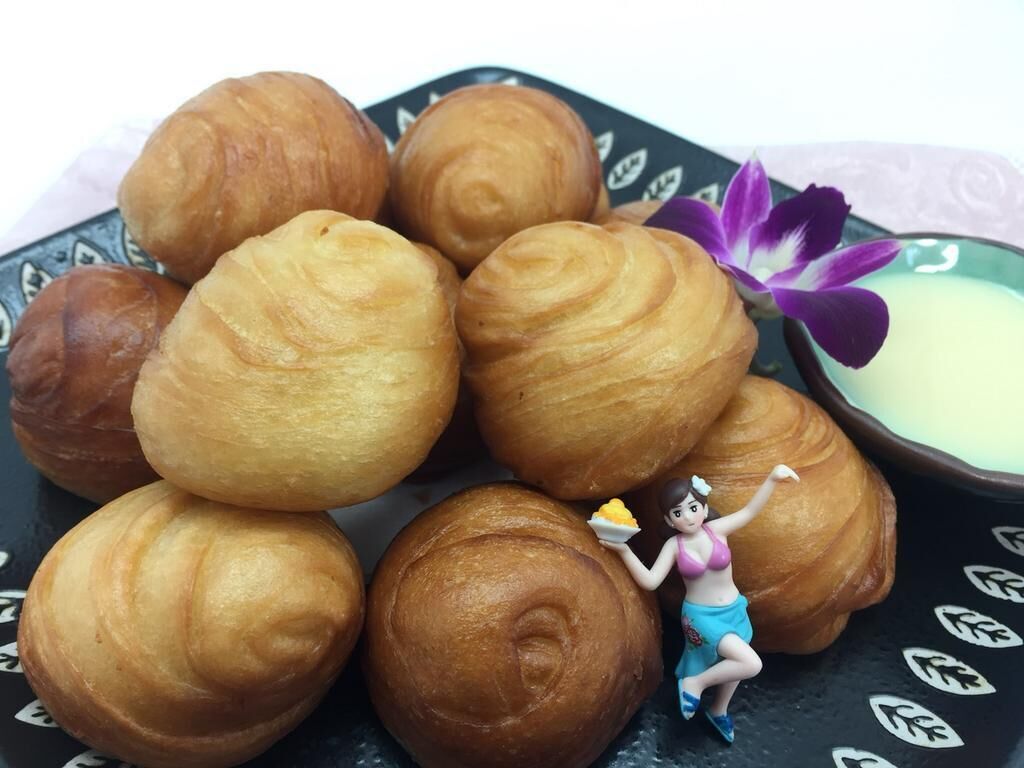 Een bord met goudbruine gebakjes, een decoratief figuurtje en een paarse bloem.