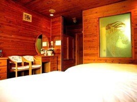 Una habitación de cabaña de madera con una cama, un escritorio con una silla, un espejo y un cuadro en la pared.