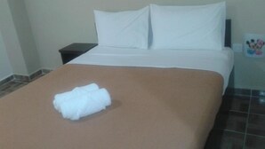 Ein ordentlich bezogenes Bett mit weißer Bettwäsche und einem gefalteten weißen Handtuch.