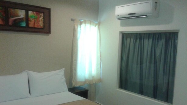 Ein Hotelzimmer mit Bett, einem fensterbelaubten Fenster, einer Klimaanlage und einem Bild an der Wand.