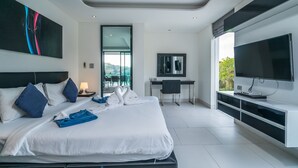 A modern hotel room with a large bed, a desk, a TV, and a balcony with a view. - Twin Sands by Lofty (Patong)
