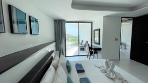 A modern hotel room with a large bed, a desk, and a balcony with a view. - Twin Sands by Lofty (Patong)