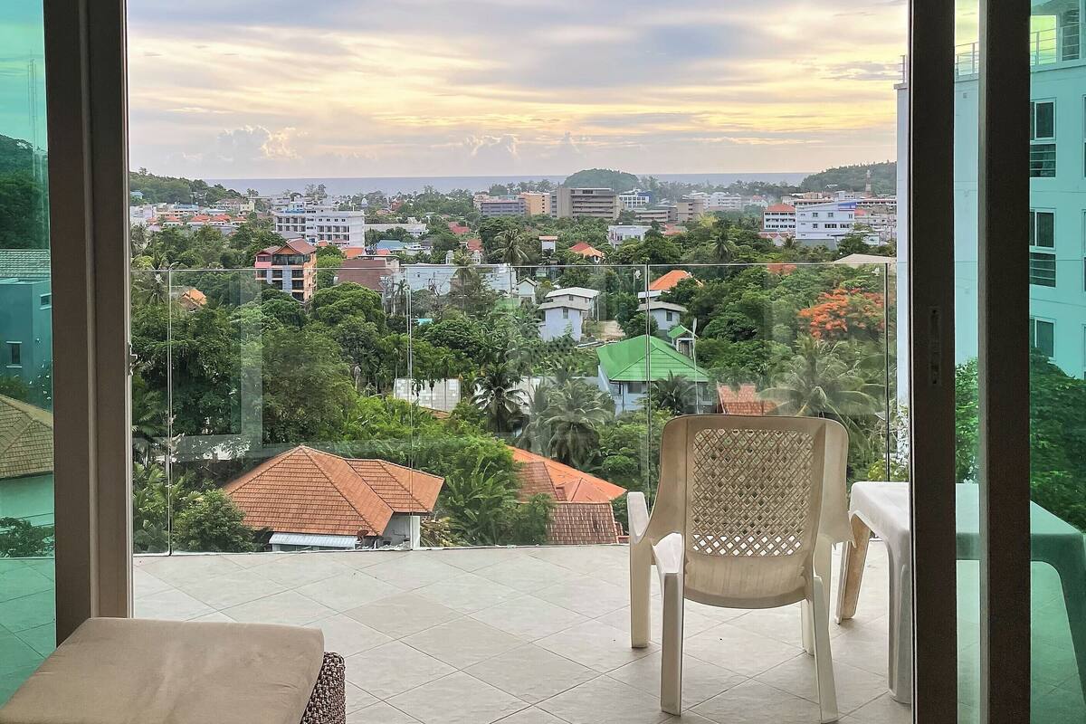 A balcony with a view of a cityscape, including buildings and greenery.