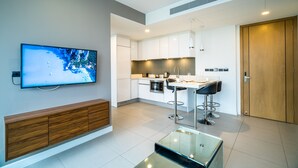 Eine moderne Küche mit weißen Schränken, einem Essbereich mit Barhocker und einem an der Wand montierten Fernseher.