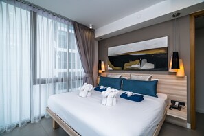 A modern hotel room with a large bed, a painting on the wall, and two bedside lamps. - Oceanstone Resort by Lofty (Choeng Thale)