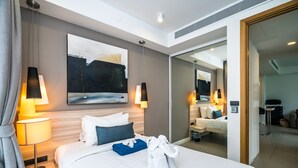 Ein modernes Hotelzimmer mit einem großen Bett, Nachttischlampen, einem Gemälde an der Wand und einem Spiegel, der das Zimmer reflektiert.