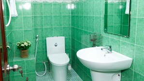 A bathroom with green tiles, a white toilet, a white sink, and a shower. - PT House (Ho Chi Minh City)