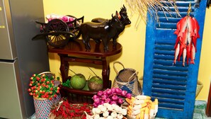 A kitchen with a refrigerator, a wooden cart with decorative items, and various food baskets. - PT House (Ho Chi Minh City)