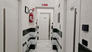 A corridor with white walls, black and white striped walls, a fire extinguisher, and a door with the number 307.