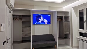 A modern room with a built-in TV, a grey sofa, and a walk-in closet.