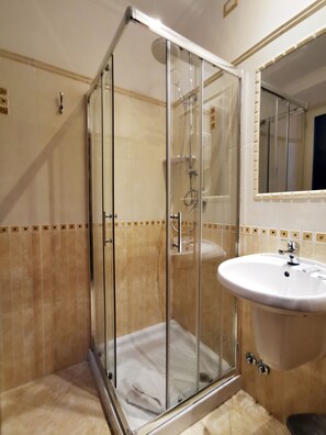 Driepersoonskamer | Badkamer | Een regendouche, een haardroger, een bidet, handdoeken