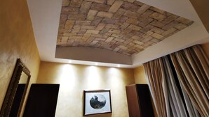A room with a brick ceiling, a framed picture on the wall, and a large window with curtains.