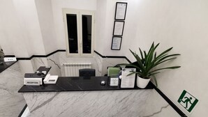 A reception desk with a marble counter, a plant, framed certificates, and a sign indicating an emergency exit.