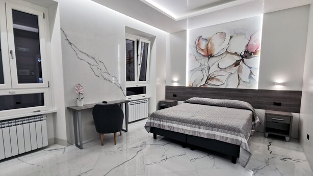 A modern bedroom with a large bed, a desk, and a radiator.