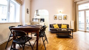A modern living room with a dining area, a sofa with cushions, and a view of the kitchen through an archway. - Kopernika Srodmiescie Apartment (Warsaw)