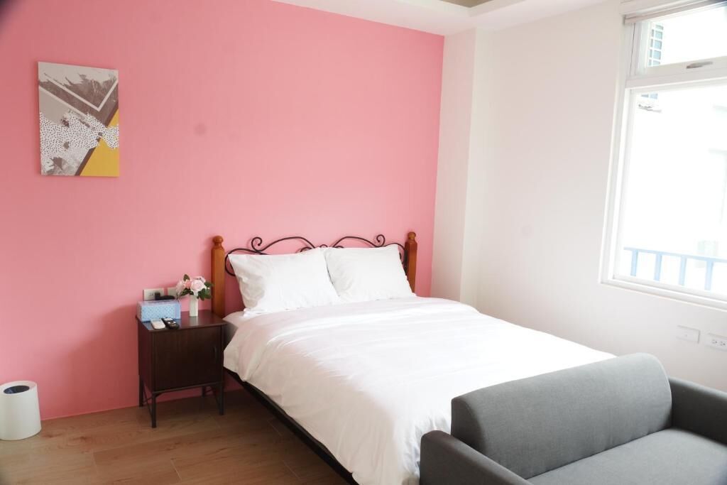 A bedroom with a bed, a nightstand, a chair, and a window.