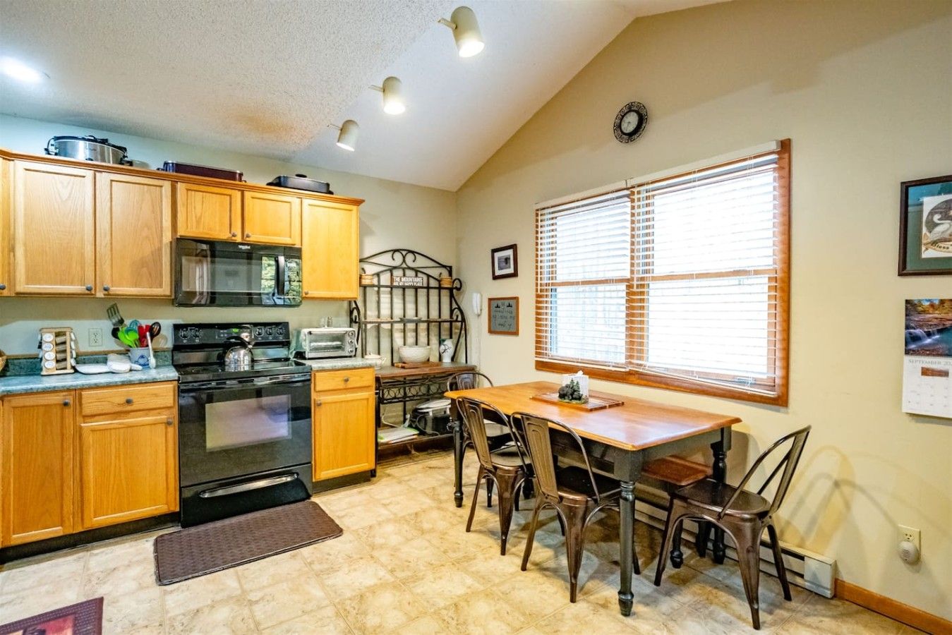 A kitchen with wooden cabinets, a stove, a microwave, and a dining table with chairs.