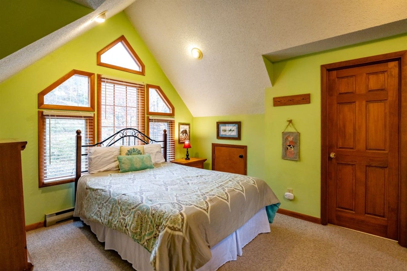 Een slaapkamer met een bed, een raam, een deur en een aan de muur hangend schilderij.