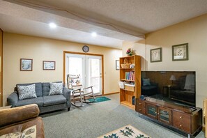 A living room with a sofa, a television, a bookshelf, and a rocking chair.