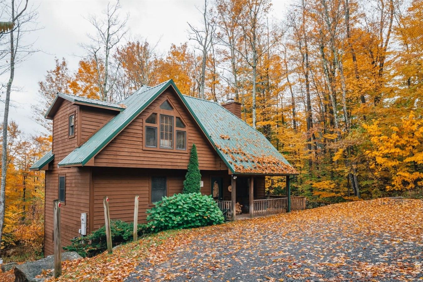 Eine Holzhütte mit Satteldach, umgeben von Herbstlaub.