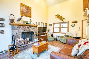 Una sala acogedora con chimenea de piedra, asientos cómodos y un televisor.