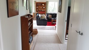 Un pasillo que conduce a una sala de estar con una estantería, un sofá y un televisor.
