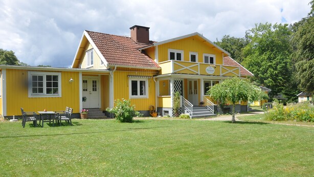 Een geel gebouw met een veranda, een trap en een kleine tuin.