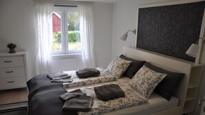 Een slaapkamer met twee bedden, een raam met gordijnen, een bedlampje en een radiator.