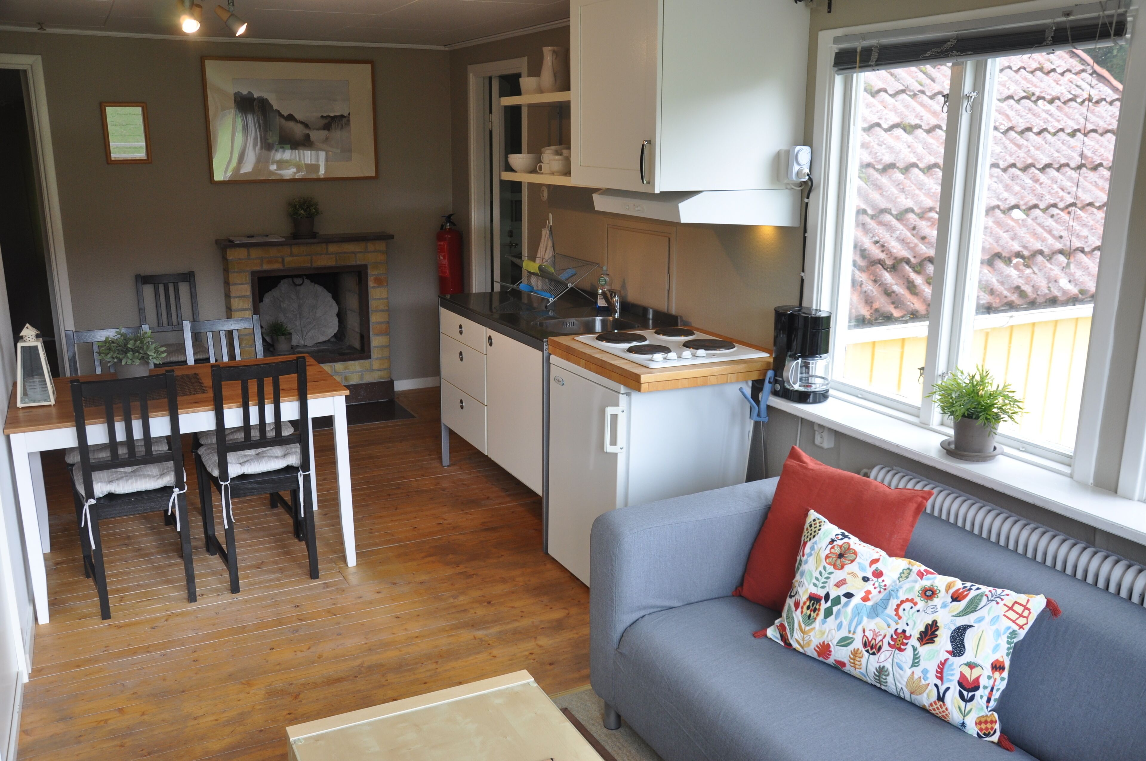 A cozy living area with a sofa, a dining table with chairs, a kitchen with a stove, and a fireplace.