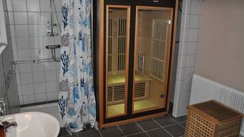 A bathroom with a shower, a sink, and a wooden cabinet.