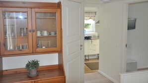 Een keuken met witte kasten, een houten kast met glazen deuren, en een kleine potplant op het aanrecht.