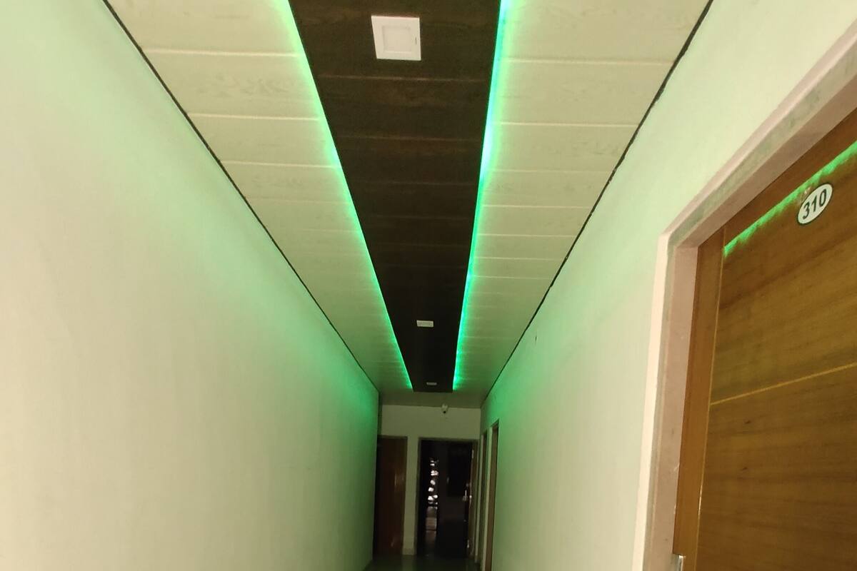 Ein Flur mit grünem indirektem Licht, einer Holztür rechts und einem gefliesten Boden.