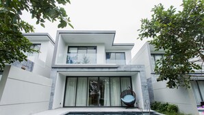 Et moderne hus med to etager og en swimmingpool foran.