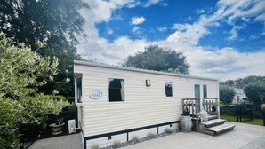 A mobile home with a patio area, a small front porch, and a sign that reads 'Vista'. - KD 814 - Vakantiepark Kijkduin (Den Haag)
