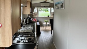 Una cocina compacta con estufa, lavamanos y un pequeño comedor con mesa y sillas.