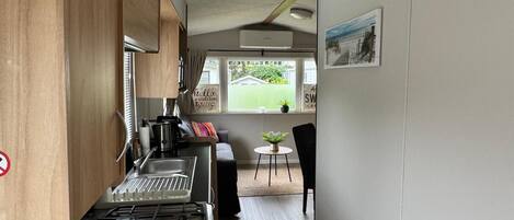 Une cuisine compacte équipée d’une cuisinière, d’un évier et d’un petit coin repas avec une table et des chaises.
