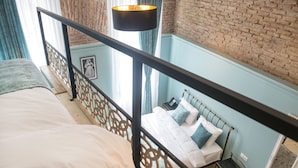 A bedroom with a bed, a nightstand, and a hanging lamp. - History of Tbilisi (Tbilisi)
