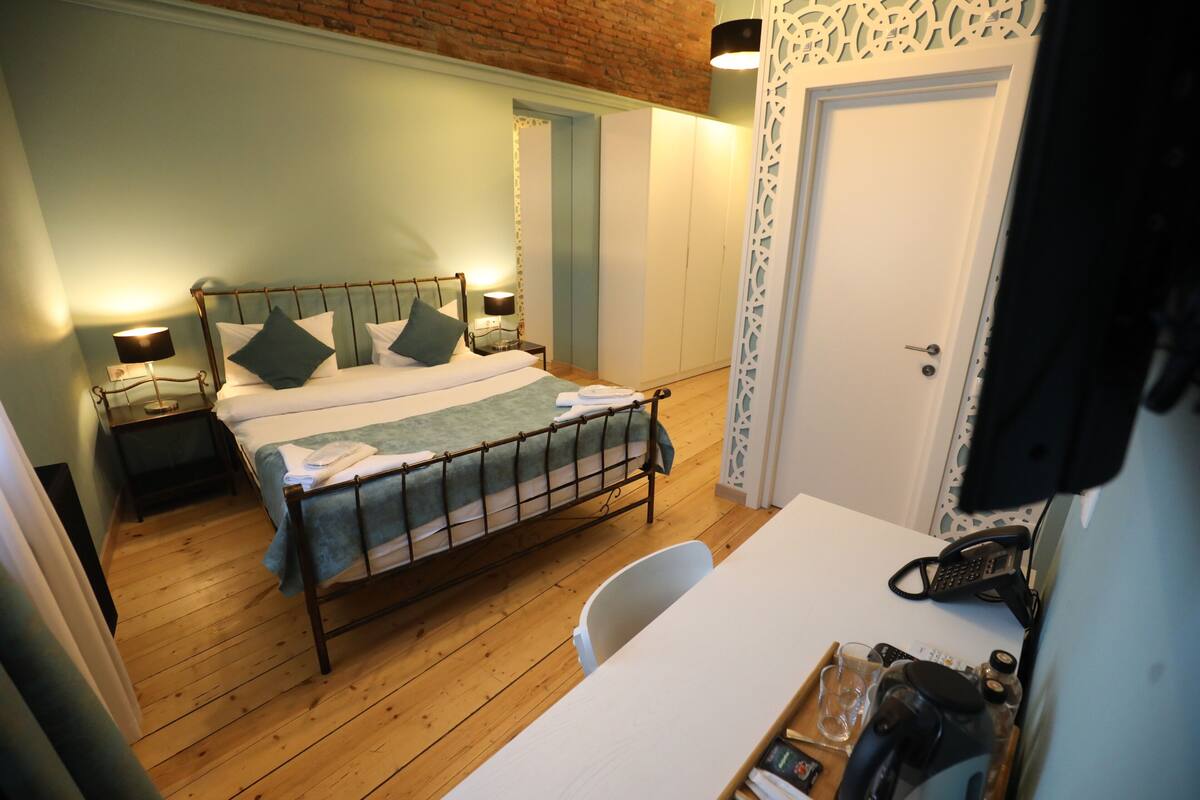 A bedroom with a bed, bedside tables, a desk, and a chair.