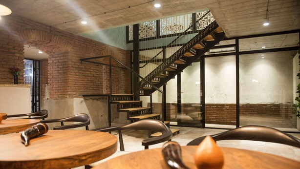 A restaurant with brick walls, wooden tables, and a staircase leading to an upper level. - History of Tbilisi (Tbilisi)