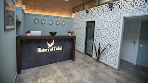 A reception desk with a logo, clocks, and a decorative wall. - History of Tbilisi (Tbilisi)