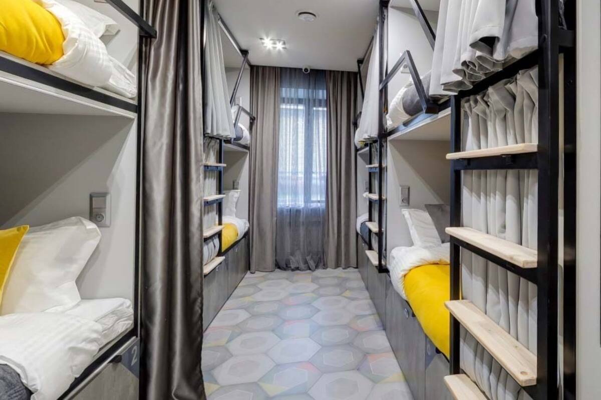 Une petite chambre à plusieurs niveaux, avec des lits superposés, des rideaux et un sol à motifs.