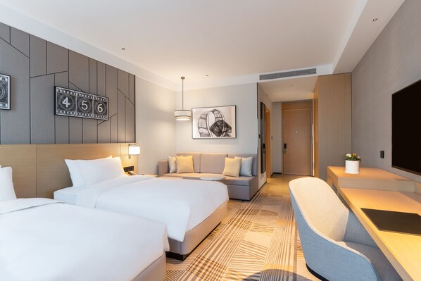 A hotel room with two beds, a sofa, a desk with a chair, a TV, and a wall-mounted artwork. - Hyatt Place Changchun Jingyue (Changchun)
