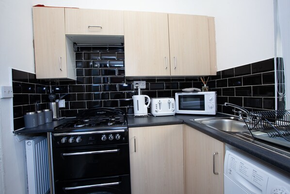 Compact kitchen with gas stove, oven, microwave, and dishwasher.