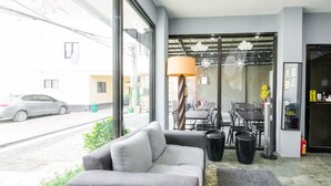 A modern living room with a sofa, a dining table, and a large window. - Super OYO 495 The Pocket Hotel (Lapu-Lapu)