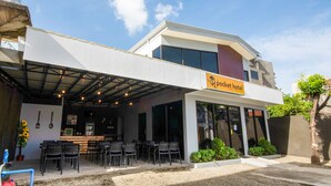 A modern building with a covered outdoor seating area, a sign reading "Pocket Hotel," and a water tower in the background. - Super OYO 495 The Pocket Hotel (Lapu-Lapu)