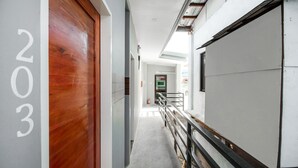 A hallway with a wooden door marked "203", a white wall, and a metal railing. - Super OYO 495 The Pocket Hotel (Lapu-Lapu)