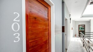 A hallway with a wooden door marked "203" and a glass railing. - Super OYO 495 The Pocket Hotel (Lapu-Lapu)