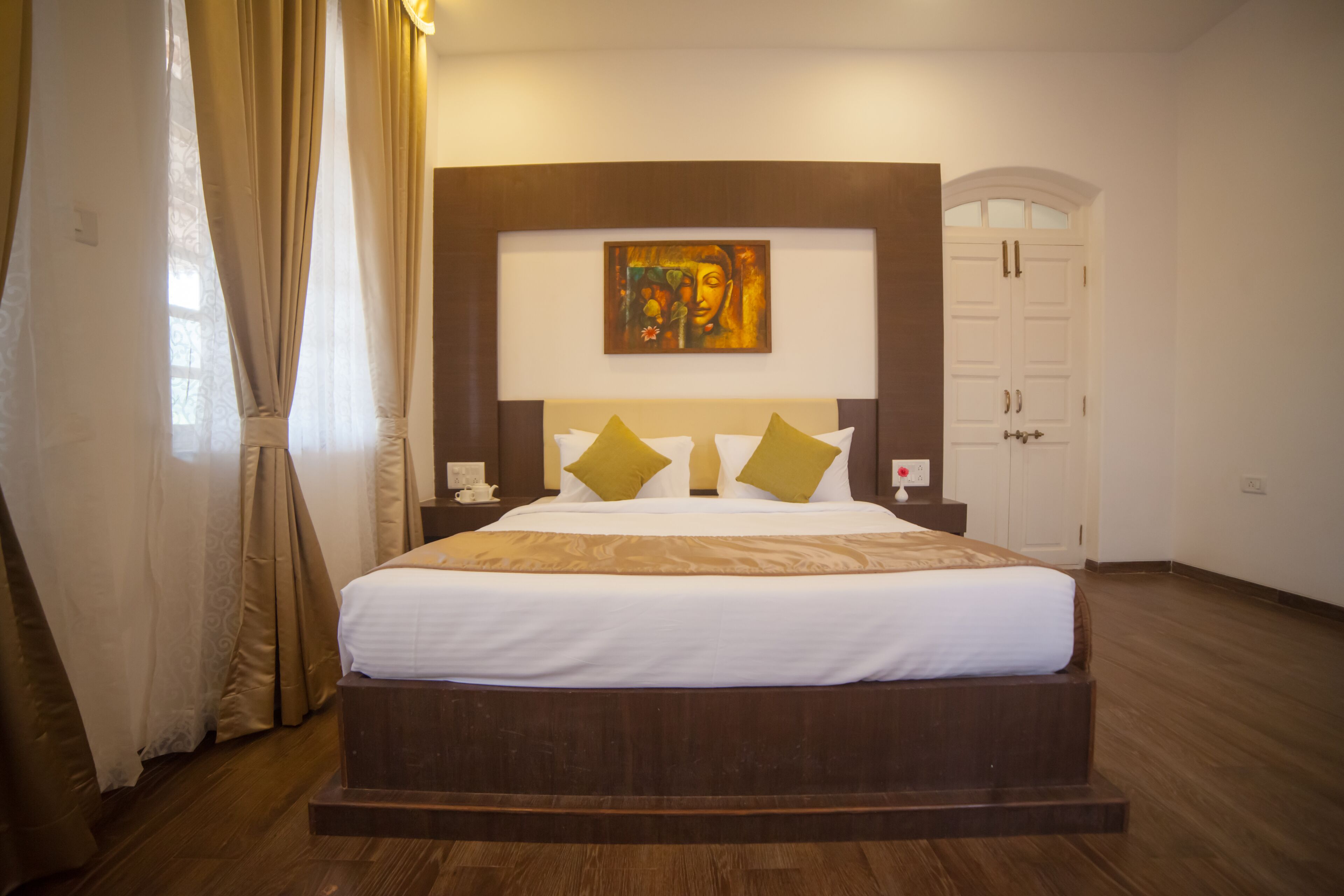 A large bed with a wooden headboard, two pillows, and a painting above it.